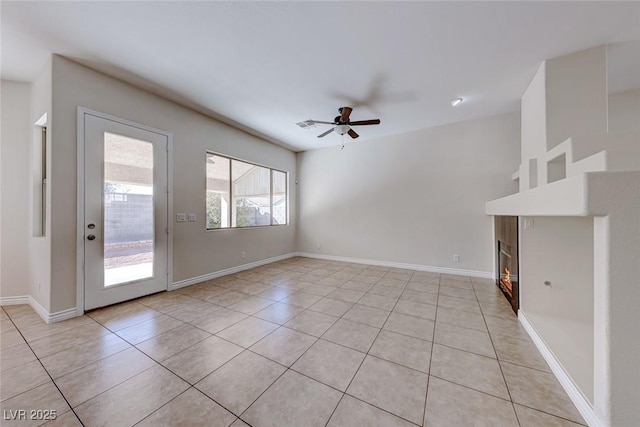 unfurnished living room featuring light tile patterned floors, ceiling fan, a fireplace, and baseboards