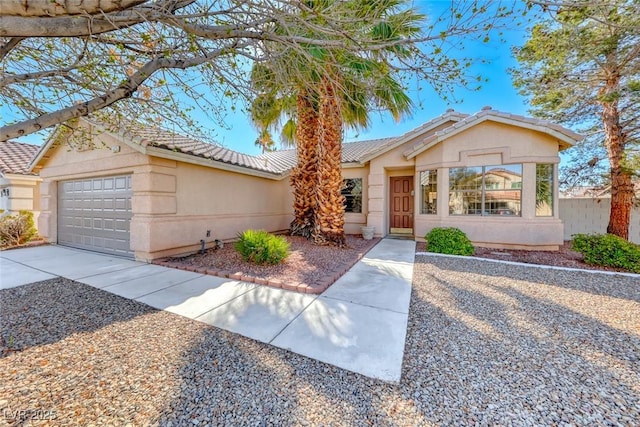 ranch-style house featuring a tiled roof, an attached garage, driveway, and stucco siding