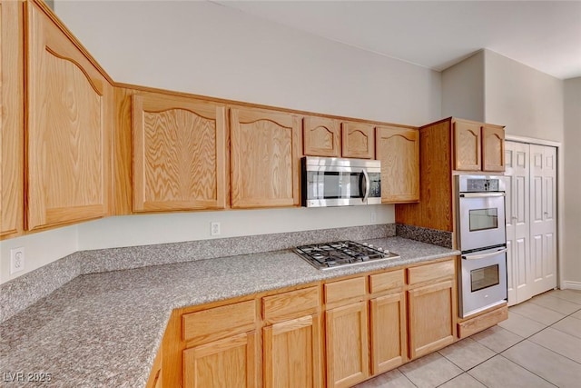 kitchen with light tile patterned floors, stainless steel appliances, light brown cabinetry, and light countertops