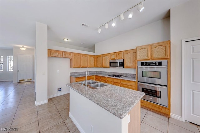 kitchen featuring light tile patterned floors, a kitchen island with sink, a sink, visible vents, and appliances with stainless steel finishes