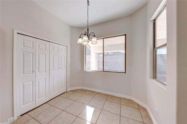 unfurnished dining area with light tile patterned floors, baseboards, and a notable chandelier