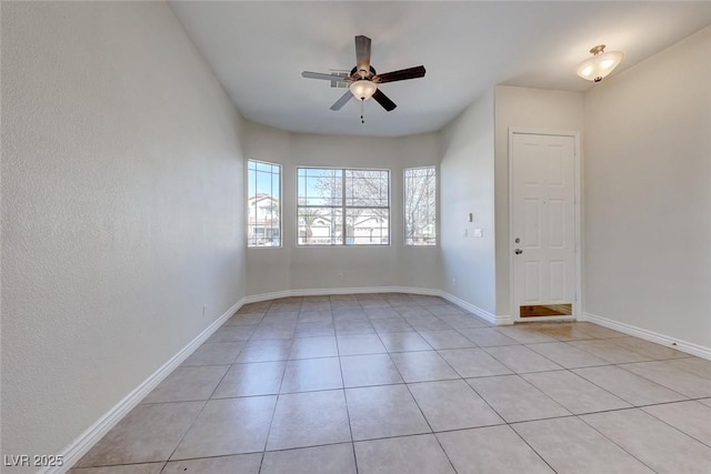 empty room with light tile patterned floors, ceiling fan, and baseboards