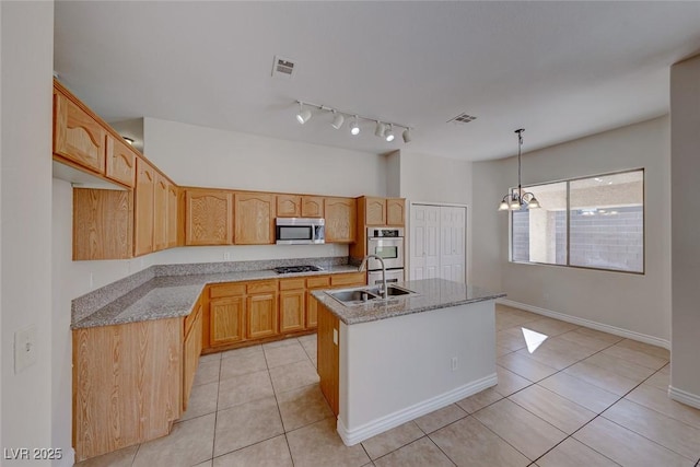 kitchen featuring visible vents, an island with sink, appliances with stainless steel finishes, decorative light fixtures, and a sink