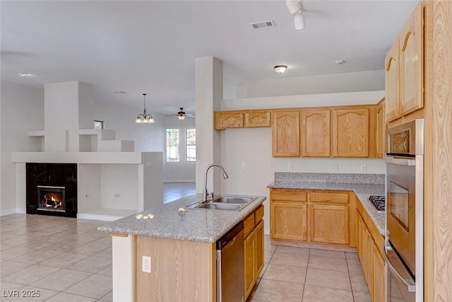 kitchen featuring light brown cabinetry, stainless steel appliances, a sink, and open floor plan