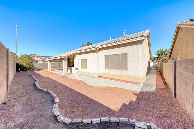 rear view of property with a patio, a tile roof, a fenced backyard, and stucco siding