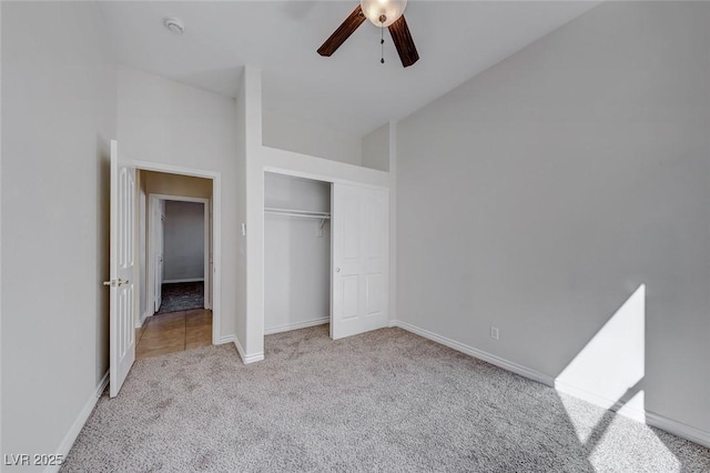 unfurnished bedroom featuring a closet, light colored carpet, a ceiling fan, high vaulted ceiling, and baseboards