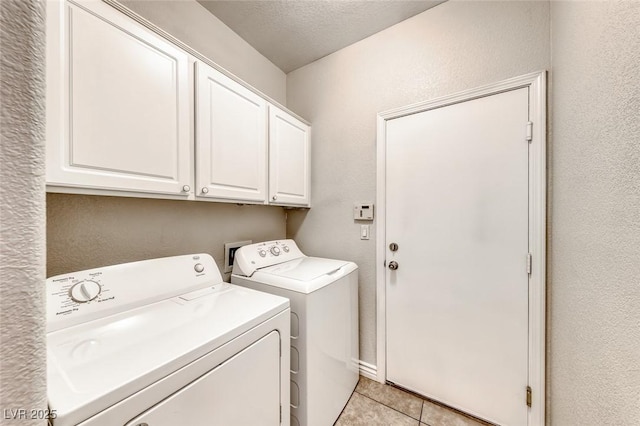 washroom with light tile patterned floors, cabinet space, a textured wall, washing machine and dryer, and a textured ceiling