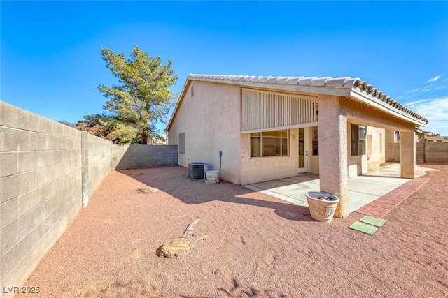 rear view of house with a patio, stucco siding, cooling unit, a fenced backyard, and a tiled roof