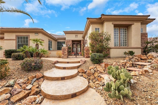 view of front of house with french doors, stone siding, and stucco siding