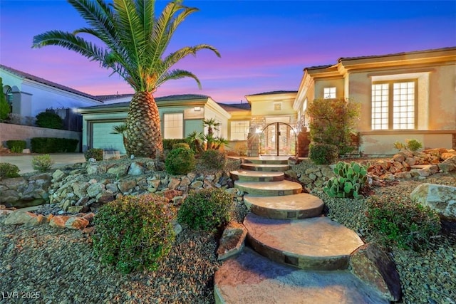 view of front facade with an attached garage, french doors, driveway, and stucco siding