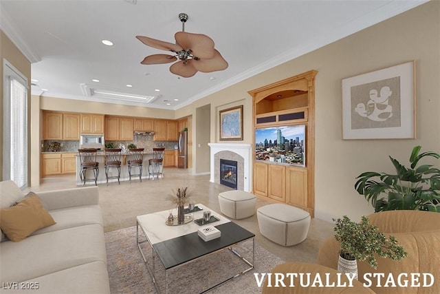 living room with a tiled fireplace, recessed lighting, crown molding, and a ceiling fan