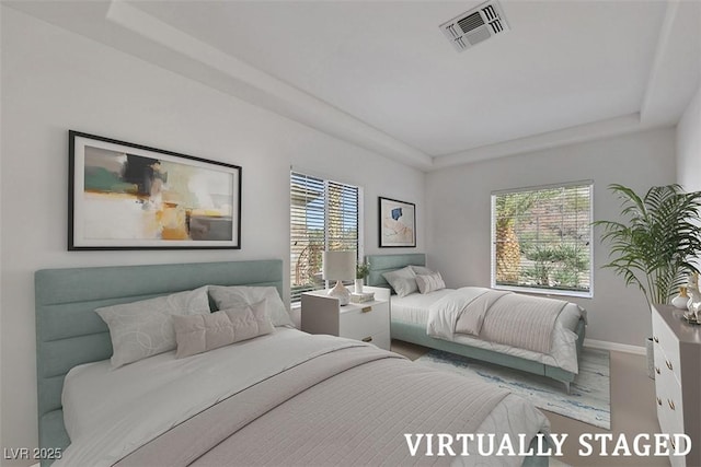 bedroom featuring visible vents, a raised ceiling, and baseboards