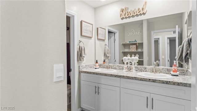 bathroom featuring double vanity, a sink, and toilet