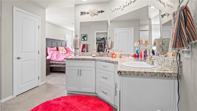 bathroom featuring double vanity, a spacious closet, a sink, and tile patterned floors