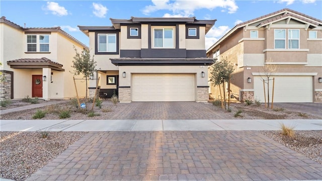 view of front facade with stone siding, decorative driveway, an attached garage, and stucco siding