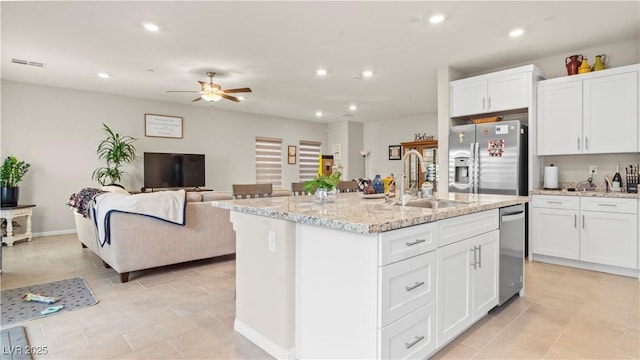 kitchen with appliances with stainless steel finishes, an island with sink, a sink, and white cabinets