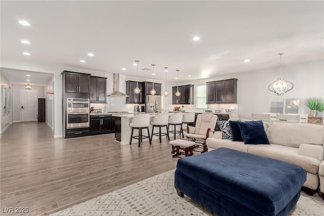 living room featuring recessed lighting, baseboards, light wood finished floors, and an inviting chandelier