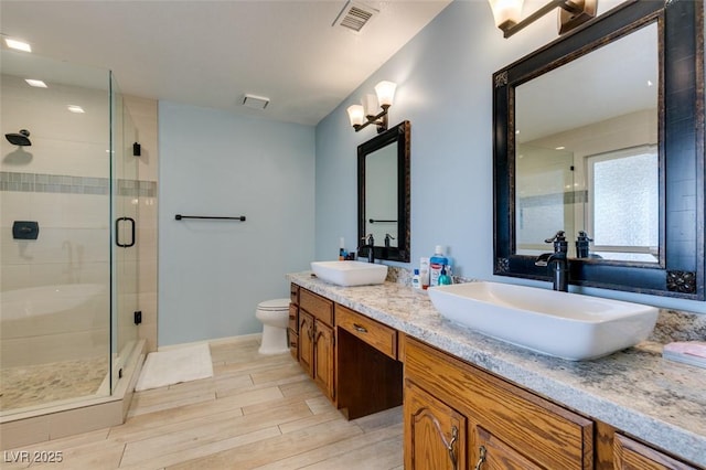 full bathroom with a shower stall, visible vents, a sink, and wood finish floors