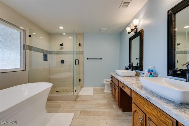 bathroom featuring a stall shower, a soaking tub, a sink, and visible vents