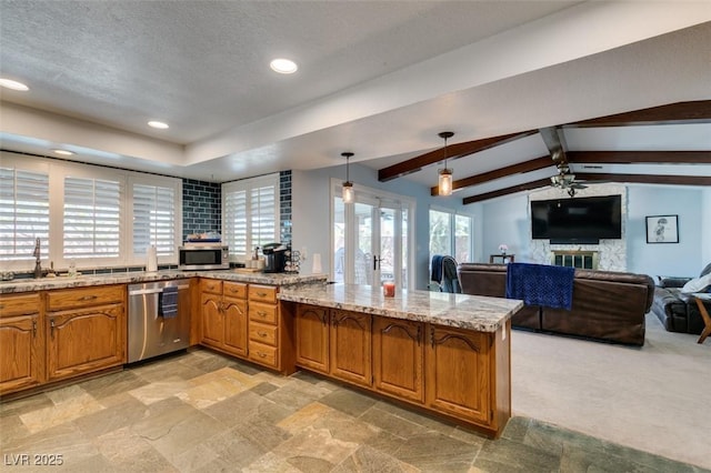 kitchen with stainless steel appliances, a peninsula, a sink, open floor plan, and brown cabinetry