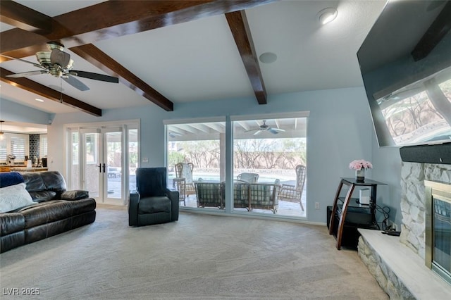 carpeted living area featuring lofted ceiling with beams, ceiling fan, french doors, and a stone fireplace