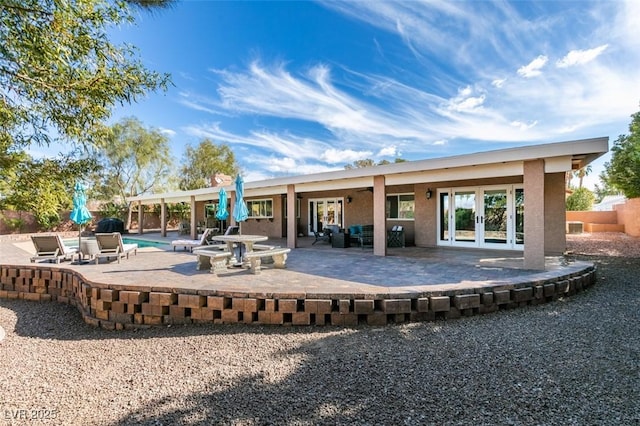 back of house featuring stucco siding, an outdoor pool, french doors, and a patio