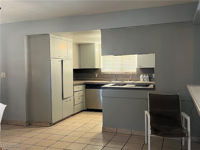 kitchen with stainless steel appliances, tasteful backsplash, light tile patterned flooring, and light countertops