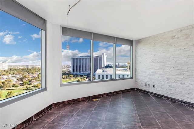 spare room featuring a view of city, plenty of natural light, dark tile patterned floors, and baseboards