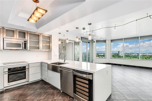 kitchen featuring beverage cooler, stainless steel appliances, a peninsula, and light countertops