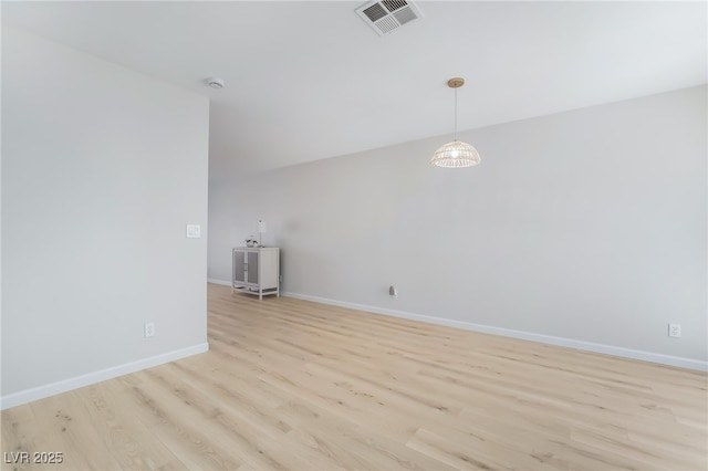 unfurnished room featuring visible vents, light wood-style flooring, and baseboards