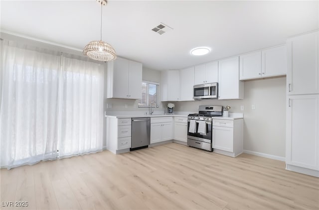 kitchen with visible vents, white cabinets, hanging light fixtures, stainless steel appliances, and light countertops