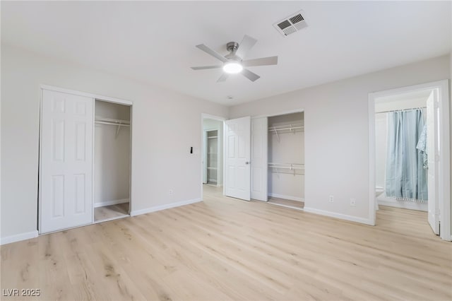 unfurnished bedroom featuring multiple closets, baseboards, visible vents, and light wood finished floors