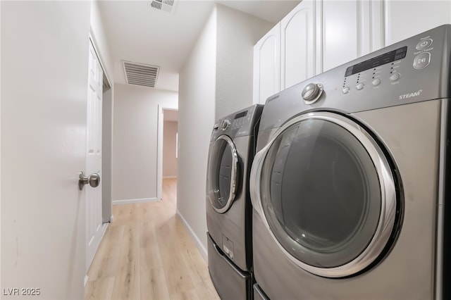 clothes washing area with cabinet space, visible vents, light wood-style floors, and independent washer and dryer