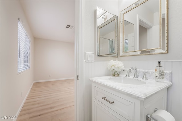 bathroom featuring baseboards, visible vents, wood finished floors, and vanity