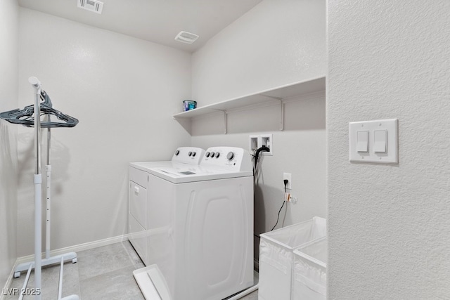 clothes washing area featuring washing machine and dryer, laundry area, visible vents, and baseboards