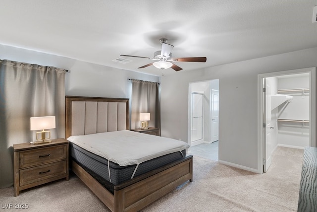 bedroom with light carpet, baseboards, visible vents, ceiling fan, and a walk in closet