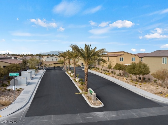 view of street with a residential view, a gated entry, a mountain view, and curbs