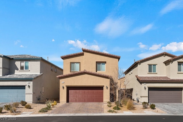 view of front of home with decorative driveway, a tiled roof, an attached garage, and stucco siding