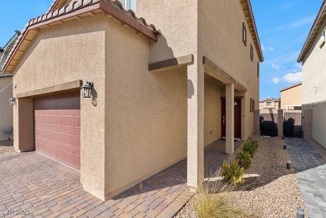 view of home's exterior featuring a tile roof, fence, an attached garage, and stucco siding