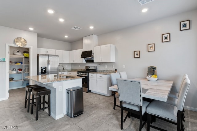 kitchen with white cabinets, a center island with sink, stainless steel appliances, and a sink