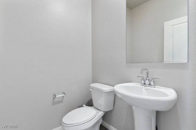 half bathroom with baseboards and toilet