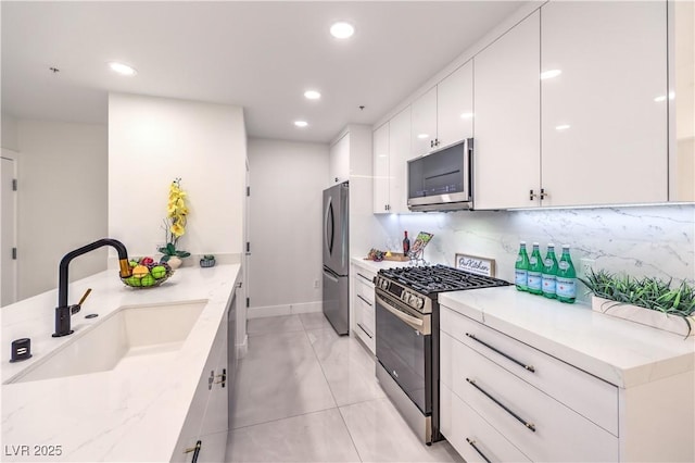 kitchen featuring tasteful backsplash, appliances with stainless steel finishes, white cabinetry, a sink, and modern cabinets