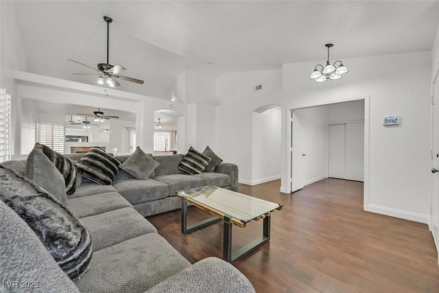 living area with arched walkways, a chandelier, dark wood-style flooring, visible vents, and vaulted ceiling