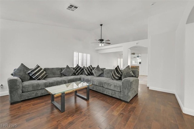 living room featuring arched walkways, ceiling fan, lofted ceiling, dark wood-style flooring, and visible vents