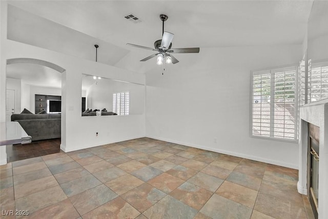 unfurnished living room featuring visible vents, arched walkways, baseboards, ceiling fan, and a fireplace