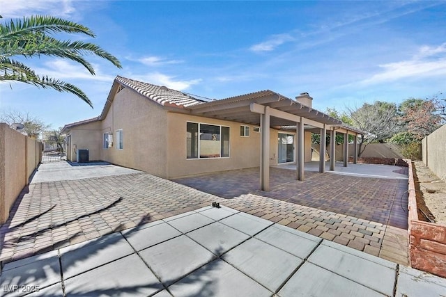 rear view of house featuring a patio area, a fenced backyard, a tile roof, and stucco siding