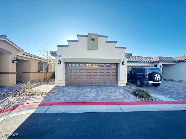 view of front of house with a garage, decorative driveway, and stucco siding