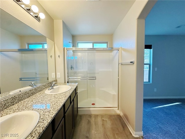 bathroom with a shower stall, baseboards, a sink, and wood finished floors