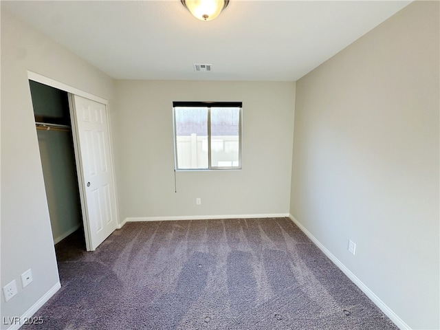 unfurnished bedroom featuring dark colored carpet, a closet, visible vents, and baseboards