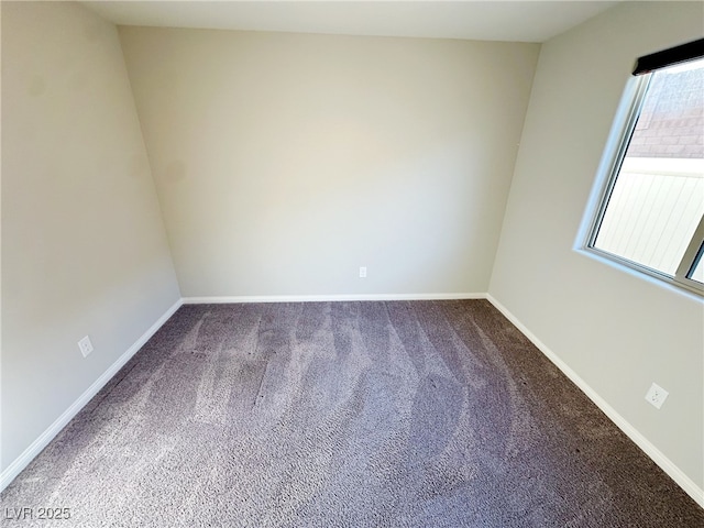 empty room featuring carpet and baseboards